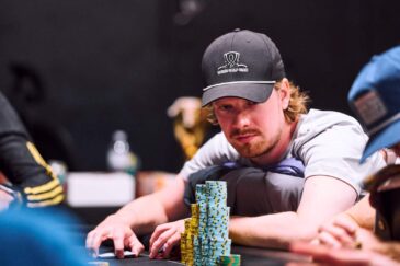 Joni Jouhkimainen istuu pokeripöydässä kasvoillaan tiukka ilme. Hänellä on päässään musta lippis ja edessään pelimerkkejä.