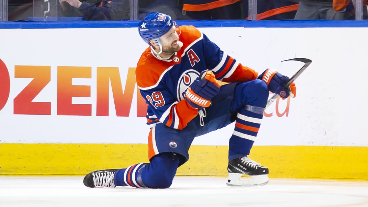 Kuvassa on saksalainen jääkiekkotähti Leon Draisaitl, joka pelaa NHL-joukkue Edmonton Oilersissa. Hän on polvistuneena yhdelle polvelle kesken ottelun, todennäköisesti tuulettamassa tekemäänsä maalia. Tämä on yksi hänen tunnetuimmista maalituuletuksistaan. Draisaitlilla on yllään Oilersin perinteinen sinioranssi peliasu, ja hänen rinnassaan on varakapteenin "A"-kirjain. Hänen pelinumeronsa on 29. Kuva on otettu NHL-ottelun aikana, ja taustalla näkyy kaukalon laita. Draisaitlin asento on voimakas ja dynaaminen, ja se vangitsee täydellisesti huippu-urheilun intensiteetin ja maalinteon riemun.
