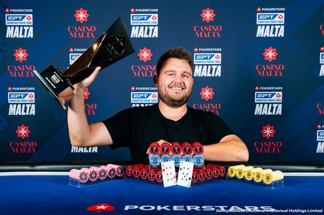 Kuvassa on onnellinen mies juhlimassa voittoaan suuressa pokeriturnauksessa. Taustalla oleva sininen mainosseinä paljastaa tapahtuman olevan PokerStarsin European Poker Tour (EPT), joka on järjestetty Maltalla. Voittaja hymyilee leveästi ja pitelee ylpeänä kädessään suurta, mustaa ja modernisti muotoiltua pokaalia. Hänen edessään pelipöydällä on valtava määrä pelimerkkejä siististi järjesteltynä näyttävään muodostelmaan. Keskellä on esillä hänen voittokätensä: herttakuutonen ja ruutukakkonen. Kuva on täynnä aitoa voitonriemua ja vangitsee täydellisesti hetken, jolloin pelaaja on saavuttanut uransa merkittävän merkkipaalun. Valokuvaaja on Danny Maxwell.