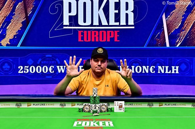 Kuvassa pokeriammattilainen poseeraa voittonsa jälkeen vihreän pelipöydän ääressä. Hänellä on yllään keltainen t-paita ja musta lippalakki, ja hänen ilmeensä on rauhallisen itsevarma. Mies näyttää kameralle kahdeksaa sormea, mikä symboloi todennäköisesti hänen uransa kahdeksatta suurta turnausvoittoa. Hänen edessään pöydällä on suuria pinoja pelimerkkejä, kaksi palkintolaattaa sekä voittokortit. Taustan sininen näyttö "POKER EUROPE" -teksteineen vahvistaa, että kyseessä on World Series of Poker Europe -tapahtuma. Kuvan on ottanut valokuvaaja Tomáš Stacha.
