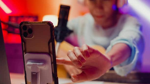 Mahdollisesti vaikuttajamarkkinointia tekevä henkilö kuvaamassa itseään, etualalla kännykkä