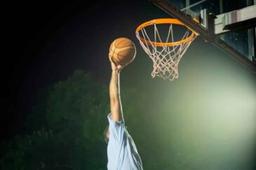 Koripalloa donkataan koriin tummaa taivasta vasten