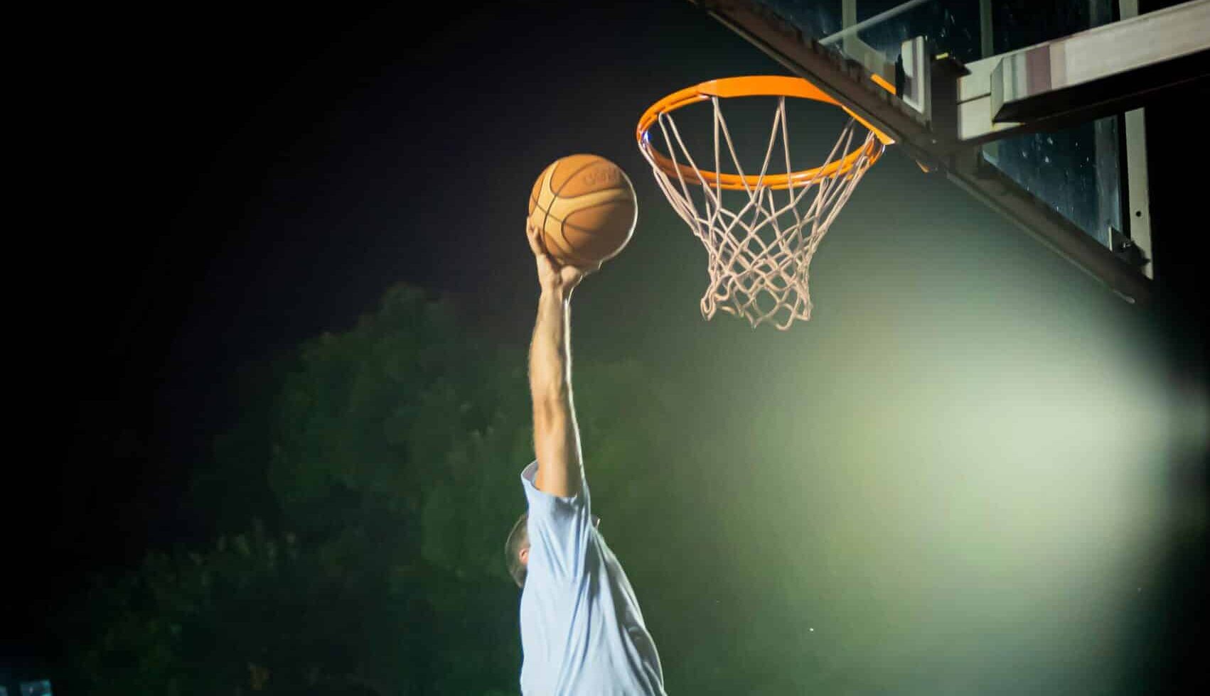 Koripalloa donkataan koriin tummaa taivasta vasten