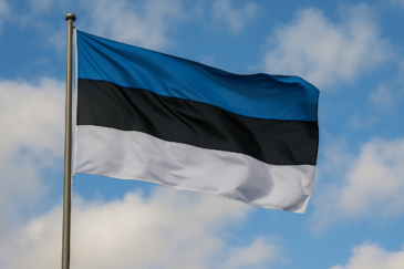 Lipputangossa heiluu Viron lippu. Lipun värit ovat sininen, musta ja valkoinen. Taustalla näkyy sinistä taivasta ja pilviä.