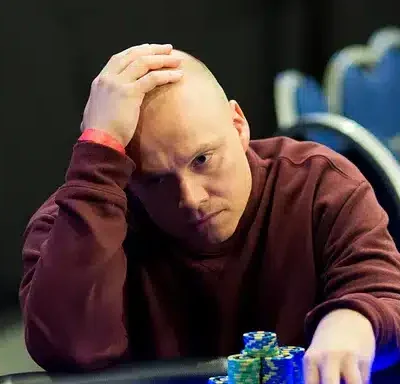 Ilari "Ziigmund" Sahamies istuu pokeripöydässä päällään punainen paita. Hänen ilmeensä on mietteliäs ja hänellä on käsi päälaella.