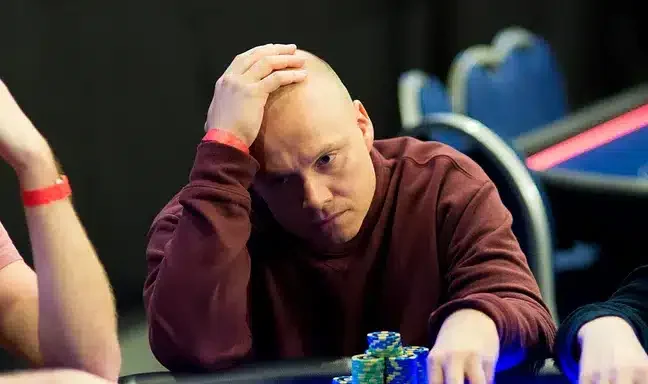 Ilari "Ziigmund" Sahamies istuu pokeripöydässä päällään punainen paita. Hänen ilmeensä on mietteliäs ja hänellä on käsi päälaella.