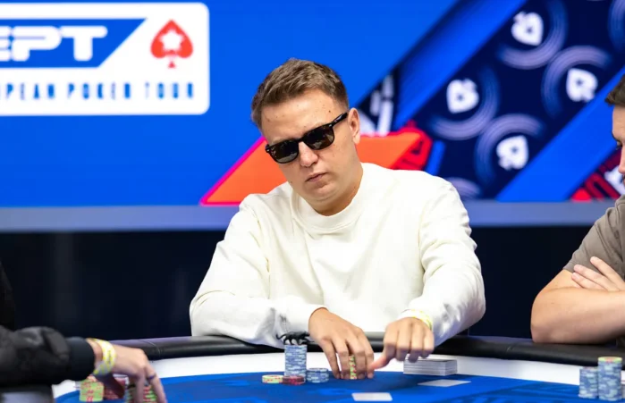 Tomasz Brzezinski istuu pokeripöydässä valkoisessa paidassa ja aurinkolasit päässään