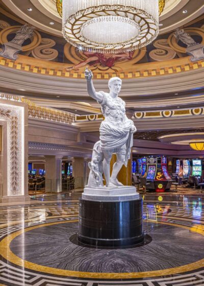 Kuvassa on Las Vegasin kuuluisan Caesars Palace -kasinohotellin pääsisäänkäynnin aula (Main Entrance Rotunda), joka uudistettiin näyttävästi vuonna 2022. Tilan majesteettinen keskipiste on keisari Augustuksen (Augustus Caesar) massiivinen, 15 jalkaa (noin 4,5 metriä) korkea valkoinen marmoripatsas. Patsas kuvaa keisaria käsi kohotettuna tervehdykseen, mikä toivottaa vieraat tervetulleiksi.