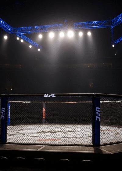 Keskellä kuvassa on vaapaaottelukehä. Kehän pohja on valkoinen. Tausta on aika tummaa, mutta taustavalot valaisevat kehää.