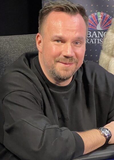 Tero Lipponen istuu pokeripöydän ääressä mustassa collegepaidassa hymyillen