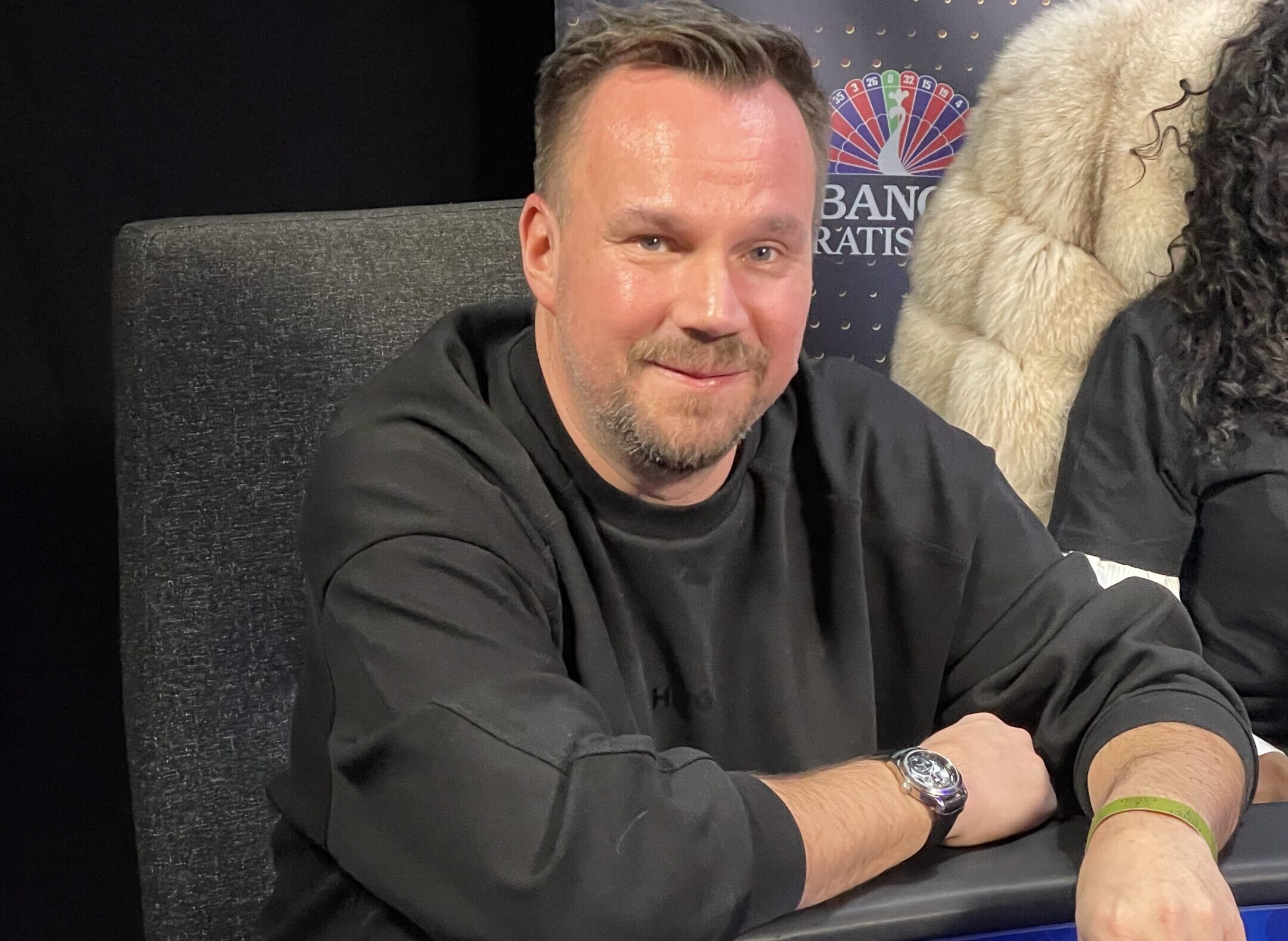 Tero Lipponen istuu pokeripöydän ääressä mustassa collegepaidassa hymyillen