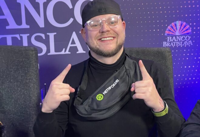 Eetu "Roosteeni" Gråsten humyilee kameralle sormet pystyssä nettipokeri.comin vyölaukku yllään