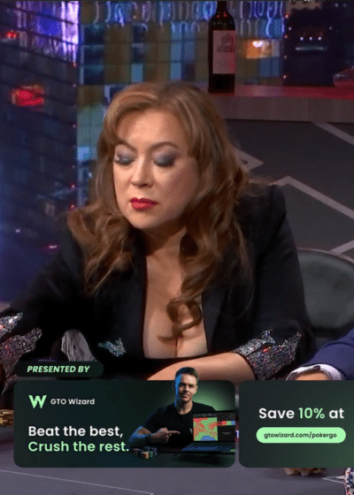 Kuvassa on näyttelijä ja pokerinpelaaja Jennifer Tilly syventyneenä peliin High Stakes Poker -televisio-ohjelmassa. Hän istuu pokeripöydän ääressä vakava ja keskittynyt ilme kasvoillaan, pukeutuneena mustaan, kimaltavilla hihansuilla varustettuun yläosaan. Ruudun grafiikat paljastavat merkittävän pelitilanteen: potissa on 214 500 dollaria. Tillyn kädeksi on merkitty pata-kuningas ja pata-kuningatar (K♠ Q♠). Taustalla näkyvä kirkas Aria-kasinon logo sijoittaa tapahtuman Las Vegasiin. Tillyn vieressä oikealla istuu mies sinisessä pikkutakissa seuraten tilannetta mietteliäänä käsi leuallaan.
