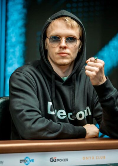 Ossi Ketola istuu pokeripöydässä. Hänellä on päällään tumma huppari. Ketolan vasen käsi on nyrkissä ja yhdessä sormessa on sormus.