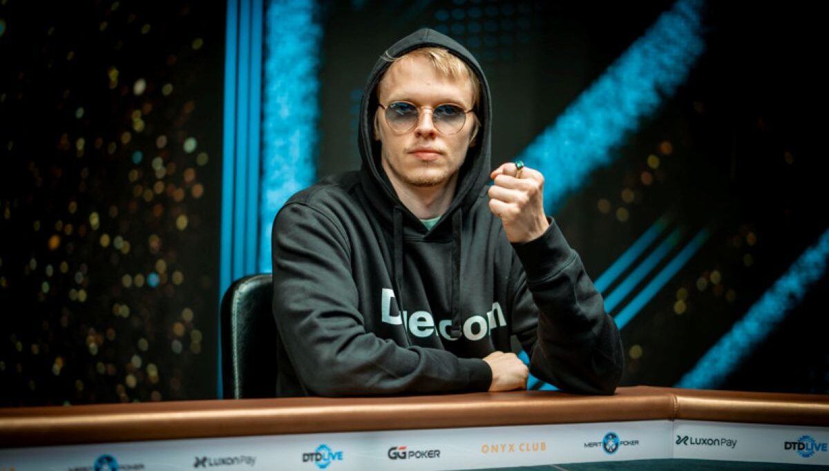 Ossi Ketola istuu pokeripöydässä. Hänellä on päällään tumma huppari. Ketolan vasen käsi on nyrkissä ja yhdessä sormessa on sormus.