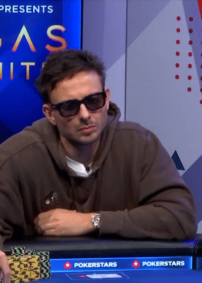 Kuvassa näkyy pokerilähetyksen kohtaus televisiostudiosta. Keskellä istuva pelaaja käyttää suuria aurinkolaseja ja ruskeaa hupparia, ja hänellä on edessään iso pino kelta-mustia pelimerkkejä. Vasemmalla puolella näkyy toinen pelaaja sivuprofiilissa. Grafiikat kertovat käden tilanteen: – Yhdellä pelaajalla on A♥ 9♦ ja hän on lyönyt $252,100. – Toisella on K♥ Q♥ ja näytön mukaan 100 % voittotodennäköisyys. Pöytäkortit ovat 3♣ K♠ J♠ 8♣ 5♦, ja potin koko on $693,900. Taustalla näkyy turnauksen visuaalinen teema ”POKERSTARS PRESENTS VEGAS INFINITE” sekä PokerGO-logo. Kokonaisuus näyttää olevan ammattimaisesti tuotettu pokeriohjelma.