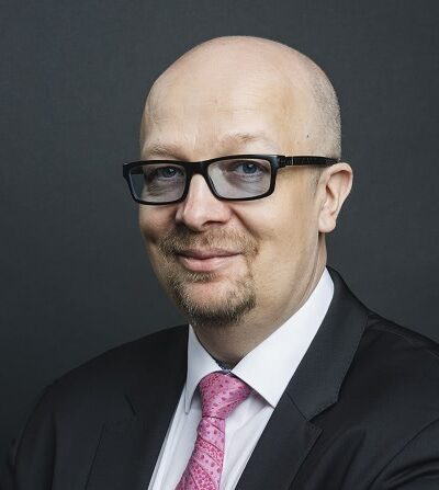 Aki Pyysing puku päällä ja siniset silmälasit päässään