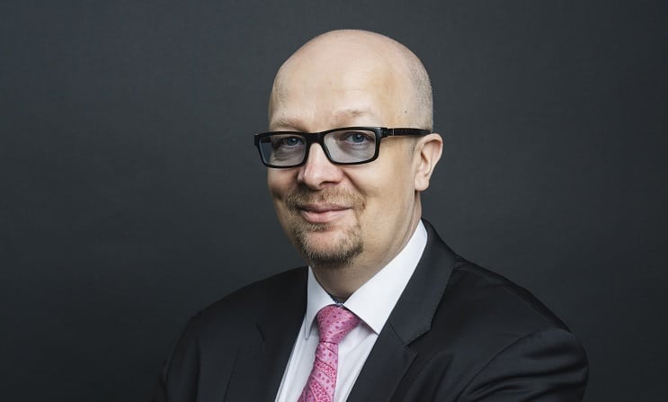 Aki Pyysing puku päällä ja siniset silmälasit päässään