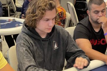 Kalle Parkkinen istuu pokeripöydässä. Hänellä on päällään tumma huppari. Parkkisen käsien alta näkyy pelikortteja ja pelimerkkejä.