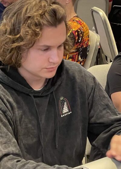 Kalle Parkkinen istuu pokeripöydässä. Hänellä on päällään tumma huppari. Parkkisen käsien alta näkyy pelikortteja ja pelimerkkejä.