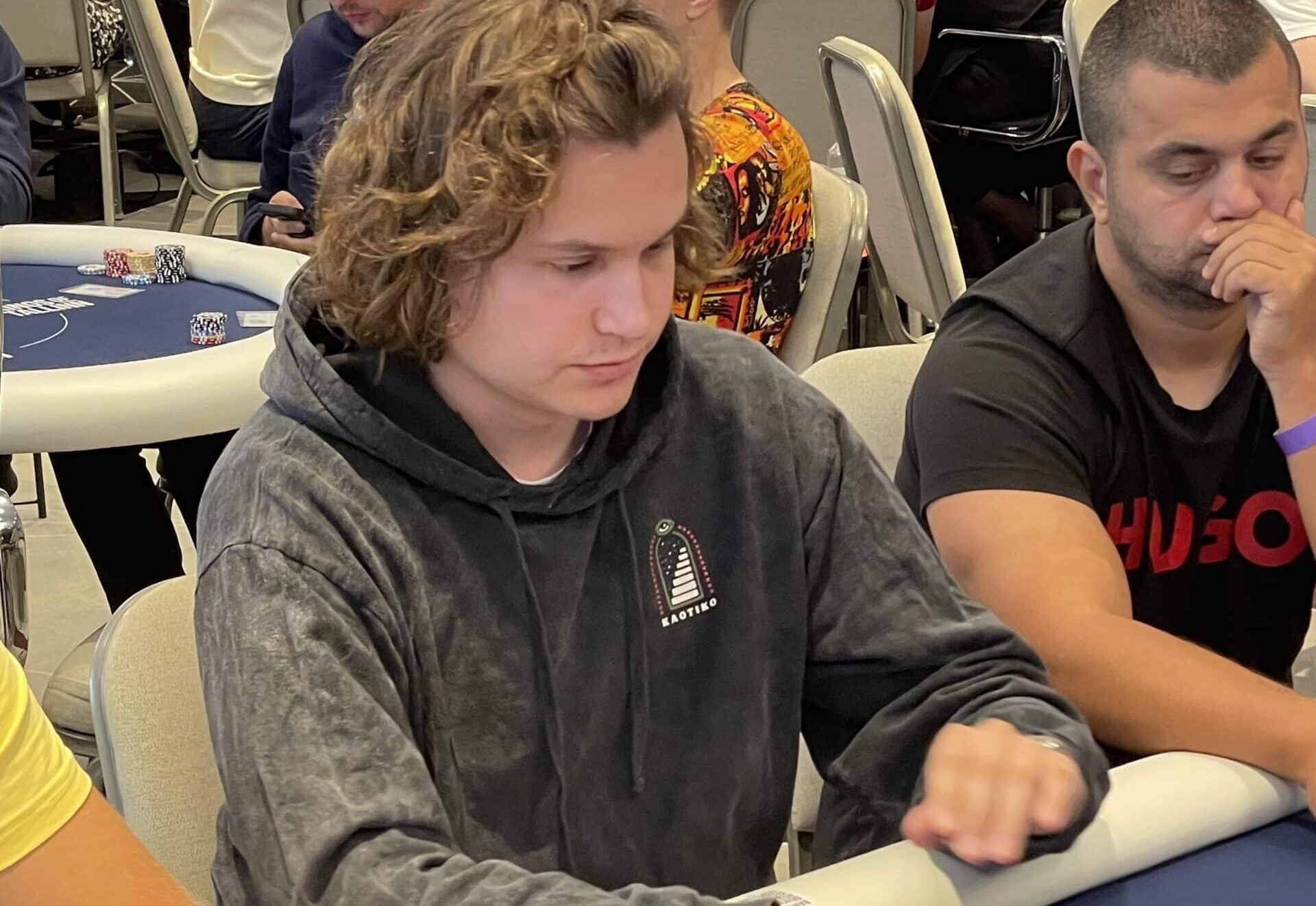 Kalle Parkkinen istuu pokeripöydässä. Hänellä on päällään tumma huppari. Parkkisen käsien alta näkyy pelikortteja ja pelimerkkejä.