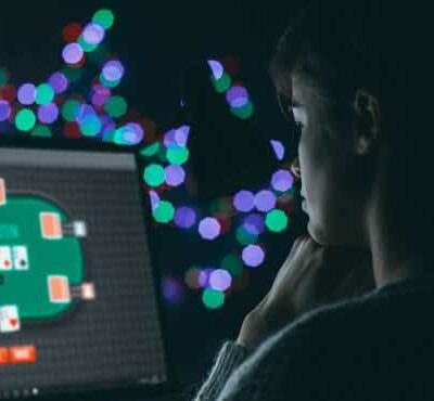 Pimeässä huoneessa on tietokoneen näyttö, jossa näkyy nettipokeripöytä. Tietokoneen edessä on nuori mies. Taustalla on valoja.