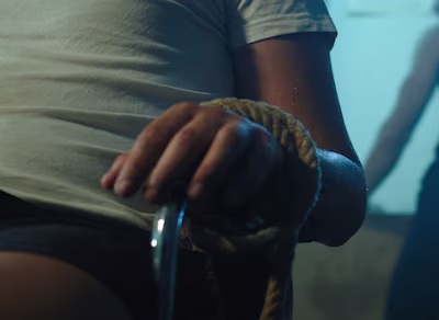 Naisen käsi sidottuna tuoliin