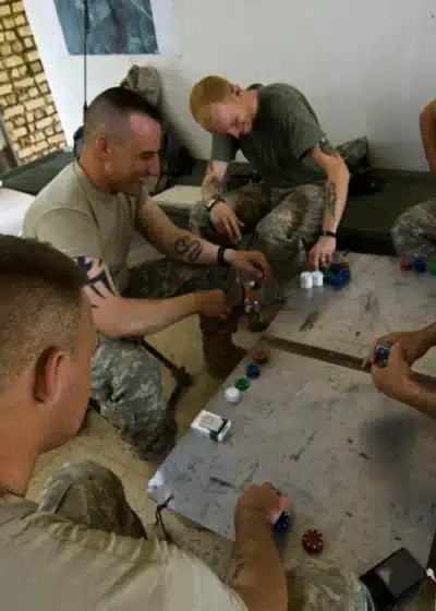 Viisi miestä pelaa pokeria pöydän ympärillä. Miehet ovat armeijassa ja heillä on päällään armeijan vaatteet.