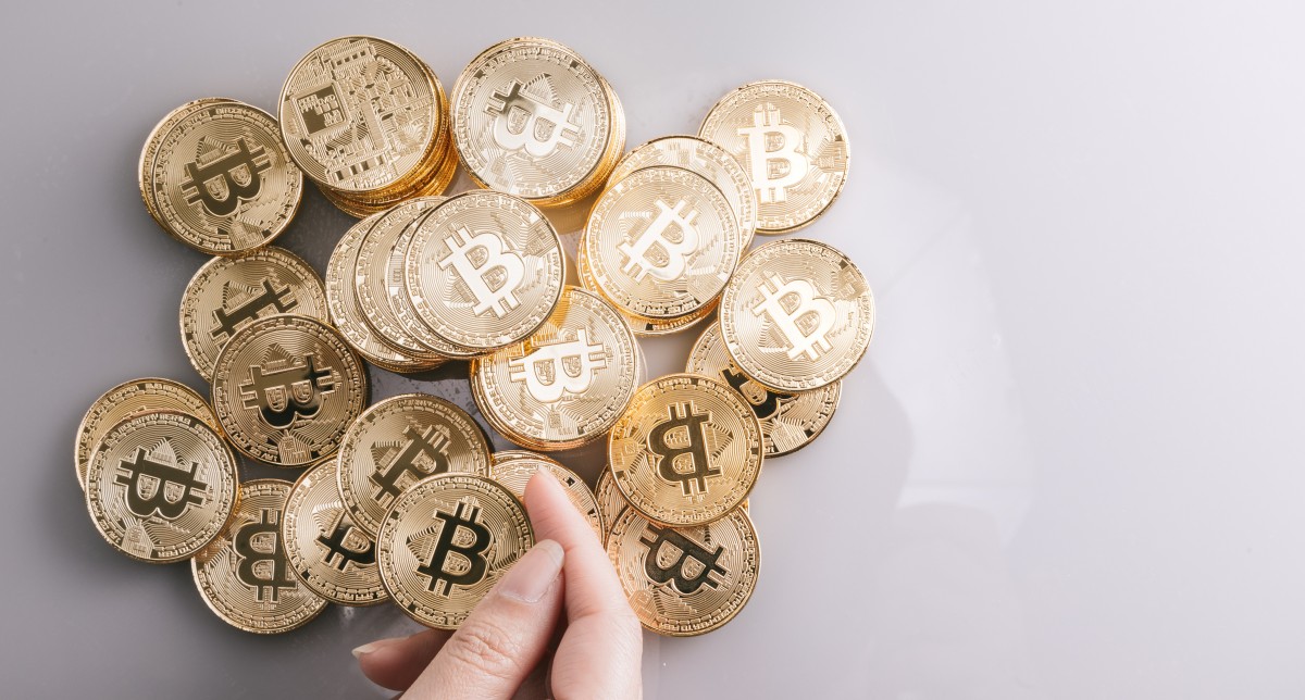 Bitcoin-kryptovaluuttaa kuvaavia kultaisia kolikoita kasassa