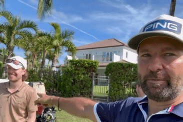 Kuvassa on kaksi miestä, molemmilla on valkoinen lippis. Toinen miehistä osoittaa toista sormella, taustalla näkyy sinistä taivasta ja palmupuita.