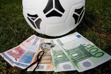 Kuvassa on jalkapallo, jonka alla on seteleitä.