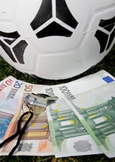 Kuvassa on jalkapallo, jonka alla on seteleitä.