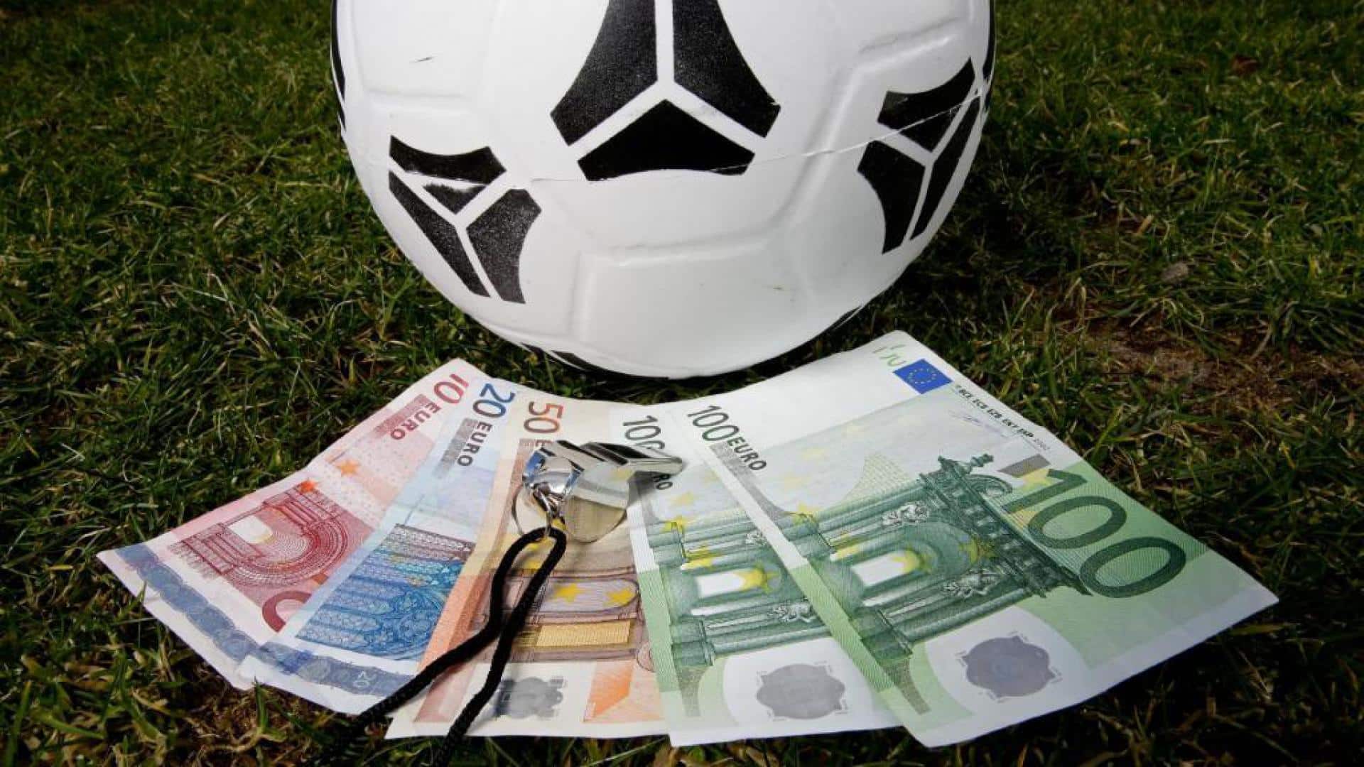 Kuvassa on jalkapallo, jonka alla on seteleitä.