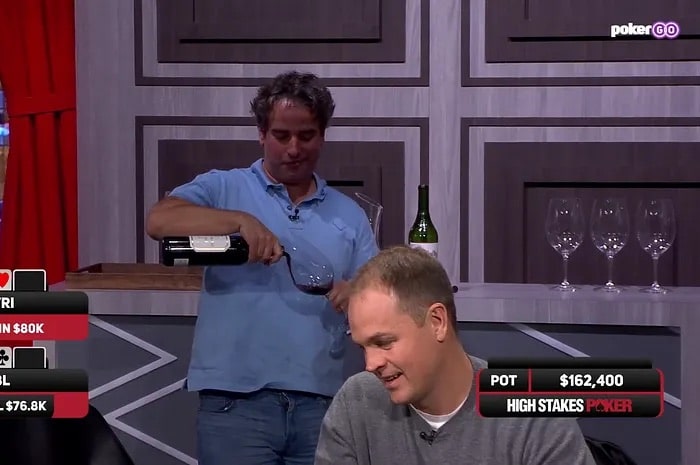 Kuvassa high stakes pelaaja Justin Gavri kaataa itselleen punaviiniä samalla kun kortteja jaetaan pöytään.