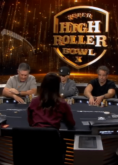 Ihmisiä istumassa pokeripöydän äärellä. Taustalla mainosseinä, jossa on "Super High Roller Bowl X " -mainos.