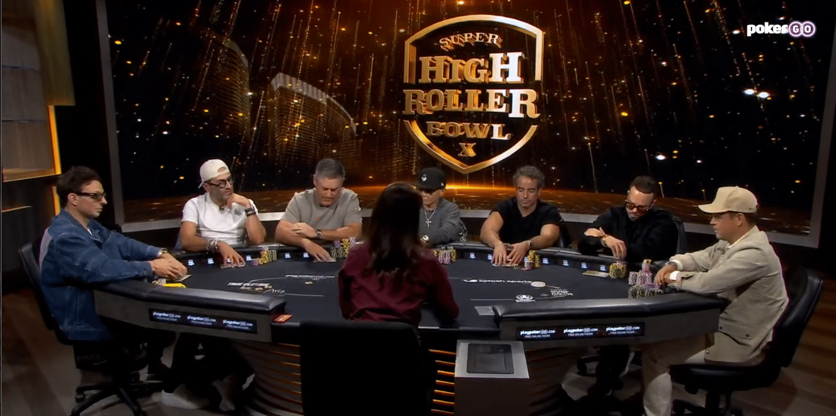 Ihmisiä istumassa pokeripöydän äärellä. Taustalla mainosseinä, jossa on "Super High Roller Bowl X " -mainos.