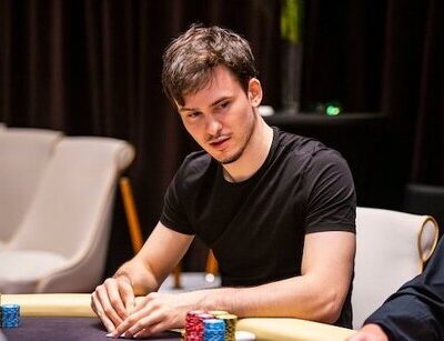 Mustaa t-paitaa käyttävä mies istuu pokeripöydän ääressä.