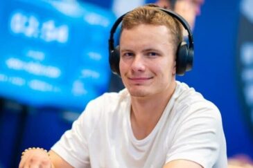 Miika Töyräs istuu pokeripöydässä. Hänellä on päässään mustat kuulokkeet ja päällään valkoinen t-paita. Tausta on sinistä.