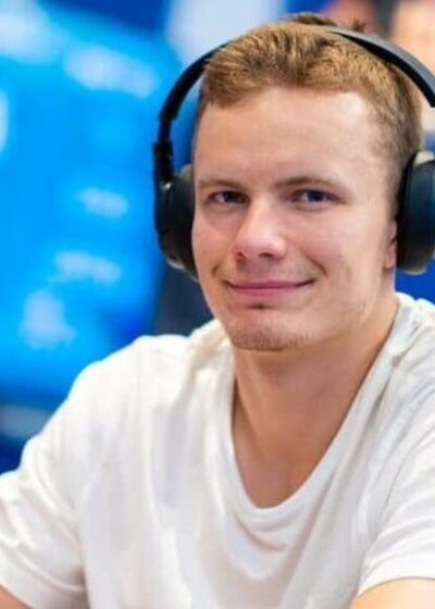 Miika Töyräs istuu pokeripöydässä. Hänellä on päässään mustat kuulokkeet ja päällään valkoinen t-paita. Tausta on sinistä.