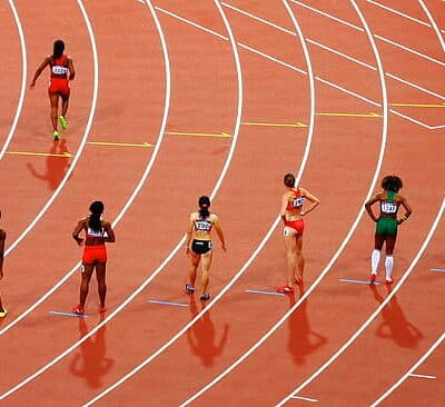 Seitsemän juoksijaa oranssilla juoksuradalla