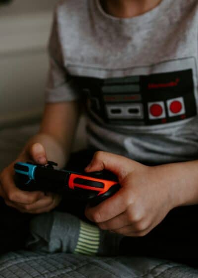 Kuvassa lapsi pelaa nintendo switch konsolilla jossa toinen puoli on sininen ja toinen punainen.