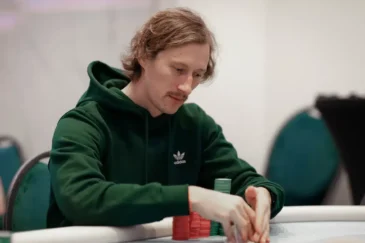 Aku Joentausta istuu pokeripöydässä. Hänellä on päällään vihreä huppari. Pöydällä Akun edessä on eri värisiä pelimerkkejä.