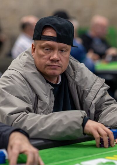 Kuvassa pokeripöydässä istuu Ilari Sahamies jolla on päällään musta pipo ja harmaa huppari. Pöytä on vihreä.