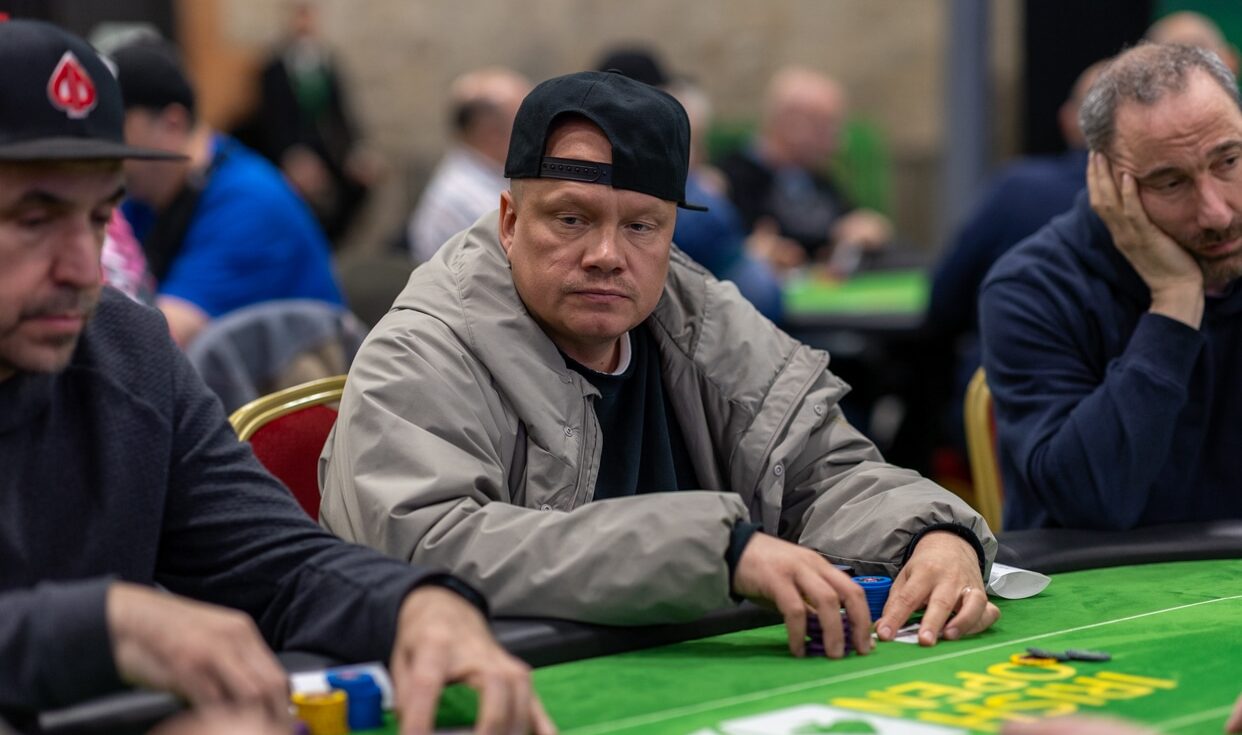 Kuvassa pokeripöydässä istuu Ilari Sahamies jolla on päällään musta pipo ja harmaa huppari. Pöytä on vihreä.