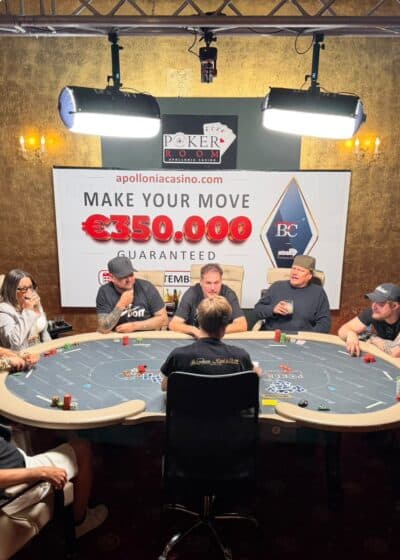 Kuvassa näkyy useita ihmisiä pokeripöydän äärellä. Taustalla on iso taulu, jossa numeroita ja seinät ovat vihreät ja keltaiset